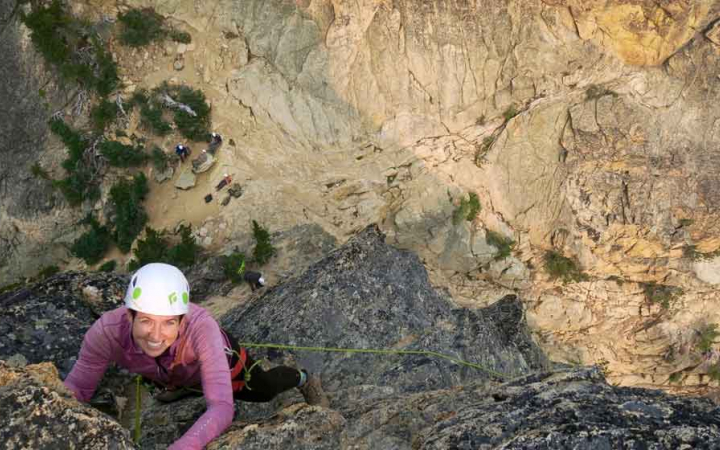a rock climber looking up and smiling as they ascend the rock wall